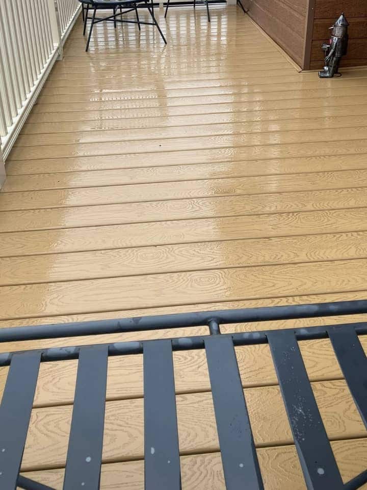 Clean sand-coloured decking, wet from washing, with a table and chairs at the far end