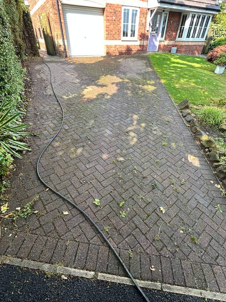 Long block-paved driveway turned almost black, with patches of moss, in front of a red brick house