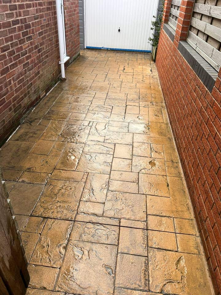 The same imprinted concrete driveway after cleaning, an even golden buff colour up to the garage door