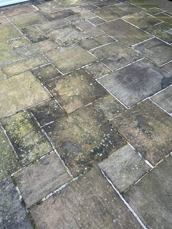 Stone patio slabs dulled grey-green with white lichen spots