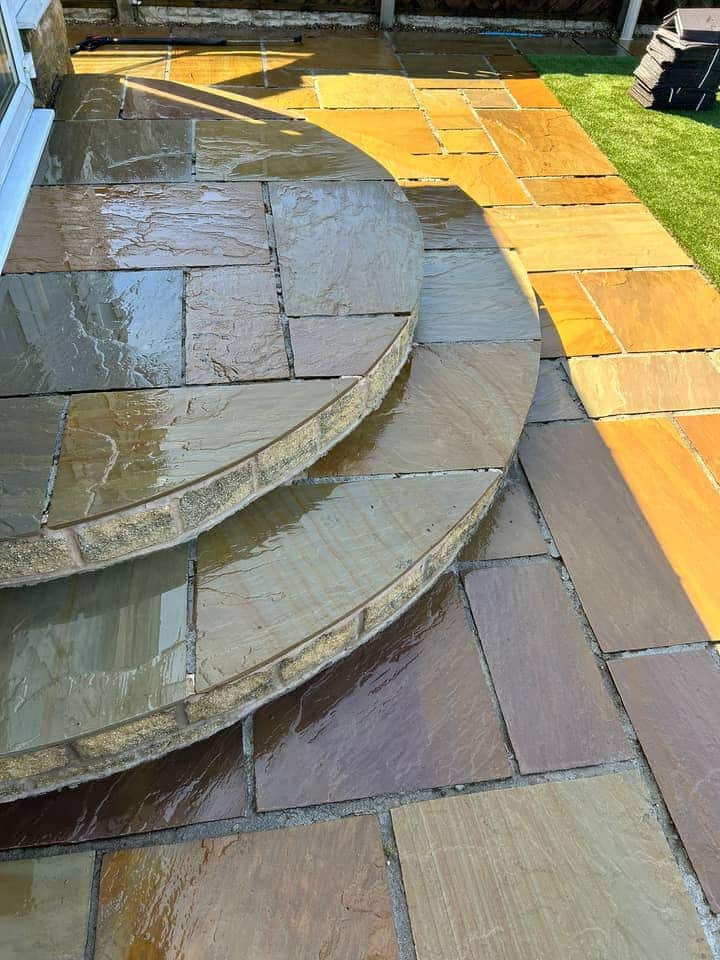 The same curved stone steps after cleaning, wet, with the buff and grey of the stone showing