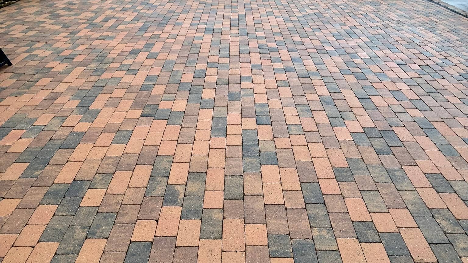A large brindle block-paved driveway after cleaning, seen low across the blocks