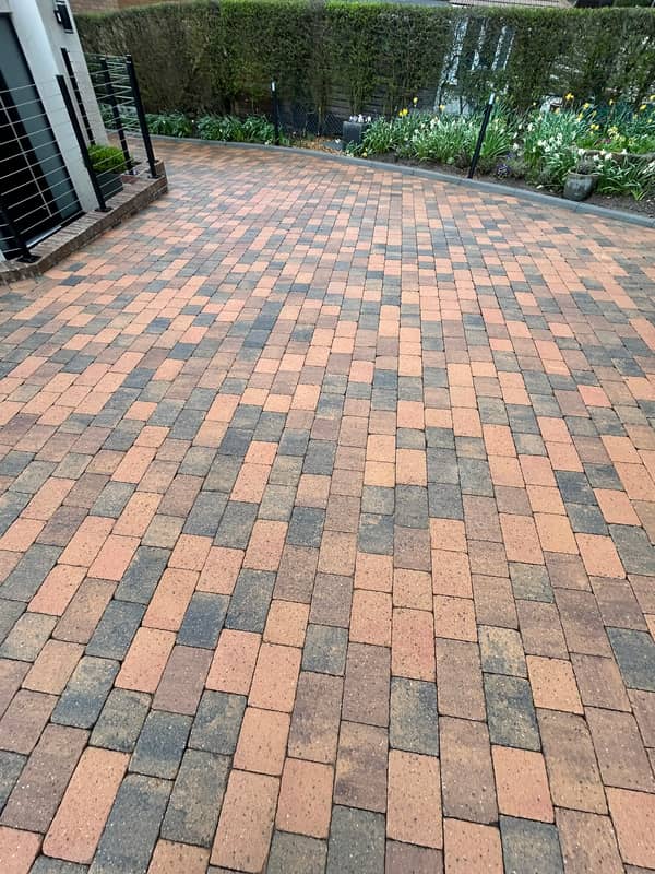 Wide brindle block-paved drive beside a flower border, after cleaning