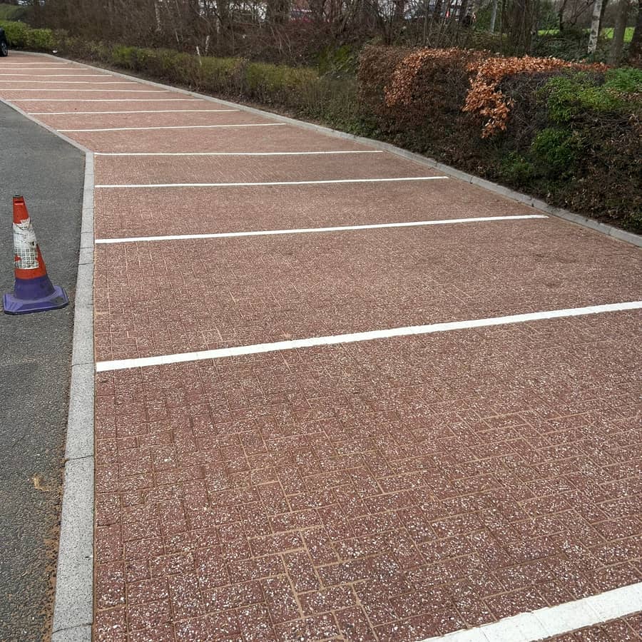 Freshly cleaned red block-paved parking bays with crisp white lines, a cone at the kerb