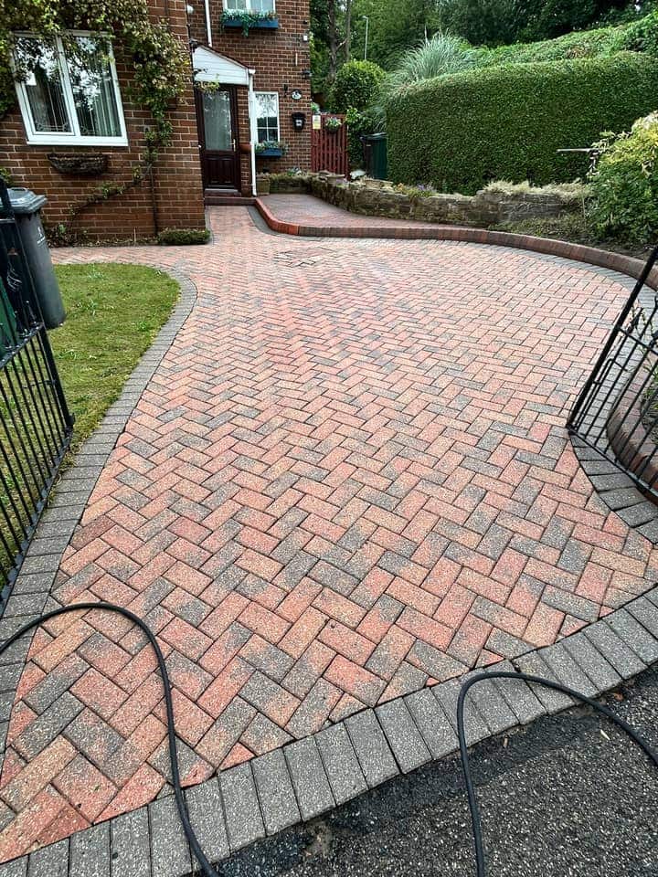 The same curved driveway after cleaning, the red herringbone blocks and grey border clearly showing
